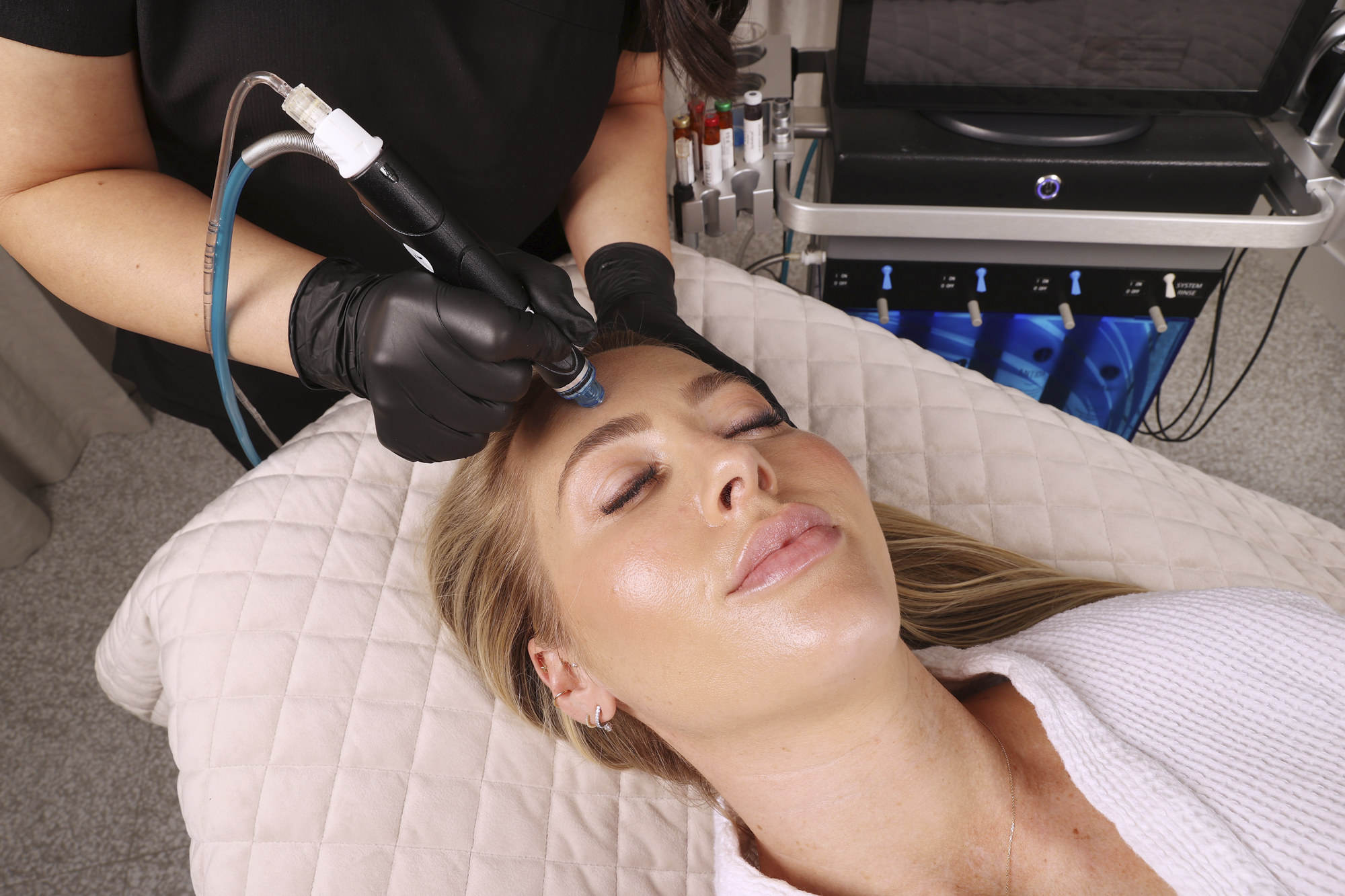Woman receiving a facial treatment with a device in a clinical setting